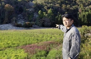 　土砂が流入した田んぼを指さす川原伸章さん＝石川県輪島市