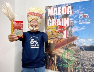 　商品化したポップコーンを手にポーズをとる農家の前田茂雄さん＝２０２５年４月、北海道本別町