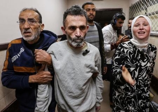 　イスラエル軍の拘束から釈放された後、ガザ中部デールバラハの病院に到着したパレスチナ人男性（中央）＝４月１０日（ロイター＝共同）