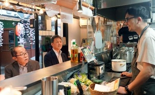 　青森県八戸市の屋台村「みろく横丁」で、カウンターに座る宮本明宗さん（中央）