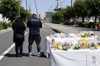 　県道陥没事故の現場周辺の献花台で手を合わせる近隣住民ら＝５月３日午後、埼玉県八潮市