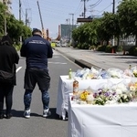 　県道陥没事故の現場周辺の献花台で手を合わせる近隣住民ら＝５月３日午後、埼玉県八潮市