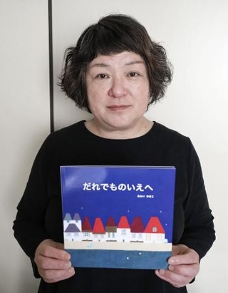 　絵本を手にする新井由木子さん＝２０２５年５月、埼玉県草加市