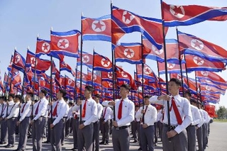 　朝鮮人民軍の前身とされる朝鮮人民革命軍の創建９３年を記念し、北朝鮮の国旗を掲げる人たち＝４月、平壌