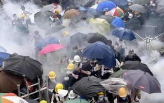 　警官隊が使用した催涙弾の白煙が立ちこめる中、逃げ惑う香港反政府デモの参加者ら＝２０１９年６月、香港（共同）
