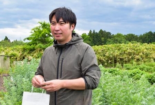 　ハーブリキュールの原料となるハーブを育てる畑に立つ老川和磨さん＝岩手県金ケ崎町