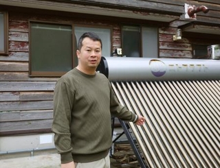　「現代集落」のプロジェクトの拠点となる古民家で、太陽熱温水器の説明をする林俊伍さん＝２０２５年６月３日、石川県珠洲市
