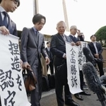 　大川原化工機訴訟の東京高裁判決を受け、「全面勝訴」と書かれた紙を手にする大川原正明社長ら＝５月、東京高裁前