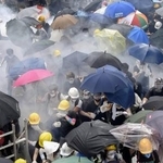 　警官隊が使用した催涙弾の白煙が立ちこめる中、逃げ惑う香港反政府デモの参加者ら＝２０１９年６月、香港（共同）