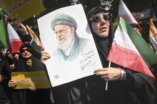 　イランの首都テヘランで営まれた国葬で、最高指導者ハメネイ師の肖像を手にする女性＝６月２８日（共同）