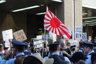 　東京都議選の街頭宣伝で旭日旗を振る支持者と、「差別をやめろ」と声をからしプラカードを掲げて抗議する人たち＝６月１５日午後、東京都杉並区のＪＲ高円寺駅前