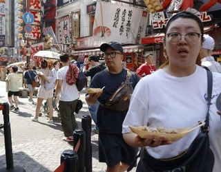 　食べ歩きをする人など、多くの観光客でにぎわう大阪・道頓堀＝７月６日