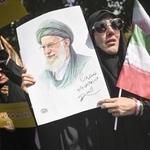 　イランの首都テヘランで営まれた国葬で、最高指導者ハメネイ師の肖像を手にする女性＝６月２８日（共同）