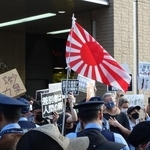 　東京都議選の街頭宣伝で旭日旗を振る支持者と、「差別をやめろ」と声をからしプラカードを掲げて抗議する人たち＝６月１５日午後、東京都杉並区のＪＲ高円寺駅前
