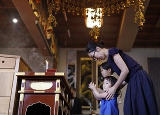 　福岡大空襲の慰霊法要で手を合わせる親子＝６月１５日午後、福岡市