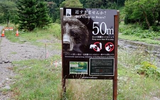 　ヒグマと適切な距離を保つことを呼びかける看板。羅臼岳登山口に向かう道に設置されている＝２０日午前、北海道斜里町