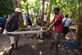 　土をふるいにかけ遺骨収集を手伝う島民＝２０２５年８月、インドネシア・ワクデ島（共同）