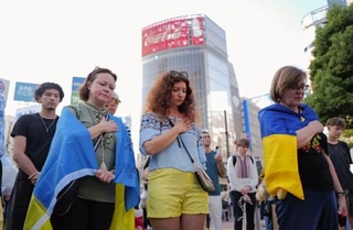 　東京・渋谷で開かれた在日ウクライナ人らによる集会で、ロシアによる軍事侵攻の犠牲者に黙とうをささげる人たち＝２４日午後