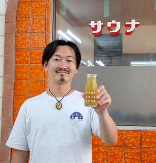 　牛乳瓶に入ったビールを手にする「上方ビール」の志方昂司社長＝７月、大阪市東淀川区