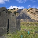 　足尾銅山の煙害で廃村となった旧松木村跡に残る墓石。後方は鉱滓（こうさい）の山＝２０１７年８月、栃木県日光市