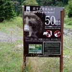 　ヒグマと適切な距離を保つことを呼びかける看板。羅臼岳登山口に向かう道に設置されている＝２０日午前、北海道斜里町