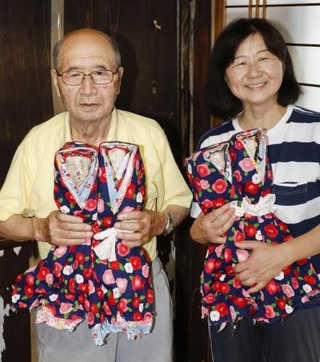 　岩手県陸前高田市の市立博物館に特別展示された「オシラサマ」を手にする佐々木慶太郎さん（左）と娘＝８月