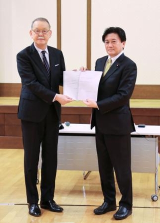 　２０２４年１２月、中教審の荒瀬克己会長（左）に諮問文を手渡す武部新文科副大臣＝文科省