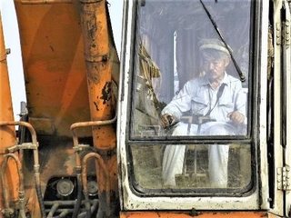 映画「荒野に希望の灯をともす」の一場面。用水路建設のためショベルカーで作業する中村哲さん（日本電波ニュース社提供）