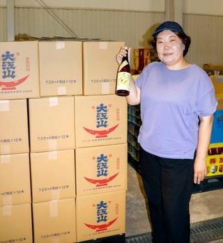 　松波酒造の日本酒を手にする金七聖子さん＝２０２５年８月、石川県小松市