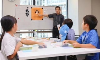 　囲碁教室で指導する喜多宏さん（奥）＝２０２５年８月、名古屋市