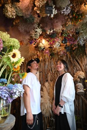 　花屋を開く夢をかなえた橋本佳尚さん（左）、久美子さん夫妻。こだわりの内装と花に囲まれて＝２０２５年７月
