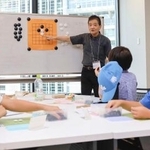 　囲碁教室で指導する喜多宏さん（奥）＝２０２５年８月、名古屋市