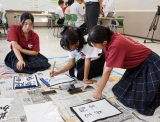 　マダガスカルから来日した学生（中央）と書道体験する生徒たち＝７月、宮崎県えびの市（同市提供）