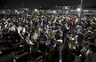 　８月、大阪メトロ中央線が運転見合わせとなり、深夜にタクシー待ちで西ゲート前に並ぶ大勢の人たち＝大阪市此花区の夢洲