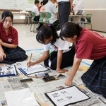 　マダガスカルから来日した学生（中央）と書道体験する生徒たち＝７月、宮崎県えびの市（同市提供）