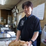 　東和交通の佃滋裕社長と事務所内でくつろぐ「ニャルソック隊」隊長の「みゃー」＝２０２５年１０月８日、広島県福山市