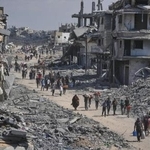 　停戦を受け、がれきの街を荷物を持って歩く避難民＝１０日、ガザ南部ハンユニス（ＡＰ＝共同）