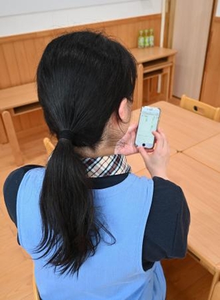 　単発バイトのアプリ画面を見る女性保育士＝９月、東京都内の保育園