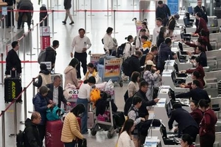 　北京首都国際空港の日本便などを扱うカウンターで搭乗手続きをする人たち＝１５日（共同）