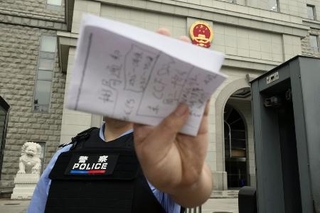 　スパイ罪で起訴された日本人男性の判決公判が開かれた北京市の第２中級人民法院前で撮影を阻止する警察官＝７月１６日（共同）