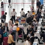 　北京首都国際空港の日本便などを扱うカウンターで搭乗手続きをする人たち＝１５日（共同）