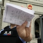 　スパイ罪で起訴された日本人男性の判決公判が開かれた北京市の第２中級人民法院前で撮影を阻止する警察官＝７月１６日（共同）