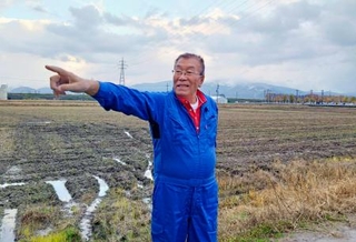 　秋起こしを終えた田んぼでコメづくりについて語る白井グループ代表の白井清志さん＝１１月２１日、福井市