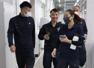 　ベトナム人の同僚たちと談笑しながら職場の工場内を歩くトゥエンさん（左）＝２０２５年１１月、群馬県藤岡市