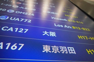 　中国が日本への渡航自粛を呼びかけてから約１カ月となる北京首都国際空港で、羽田や大阪行きなどの便名が並ぶ出発表示板＝１３日、北京（共同）