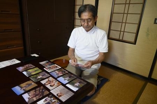 妻泰子さんの写真を見つめる荒川勉さん＝２０２４年９月、鳥取県米子市