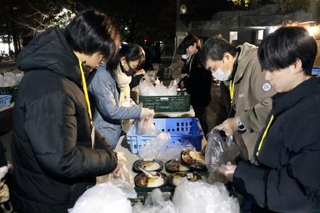　屋外で弁当など食料品の配布準備をするＮＰＯ法人「ＴＥＮＯＨＡＳＩ」の関係者ら＝１３日、東京・池袋