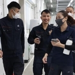 　ベトナム人の同僚たちと談笑しながら職場の工場内を歩くトゥエンさん（左）＝２０２５年１１月、群馬県藤岡市