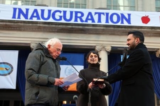 　１日、米ニューヨーク市庁舎で就任式に臨むマムダニ市長（右）と、妻のラマ・ドワジさん（中央）。左はサンダース上院議員（ゲッティ＝共同）