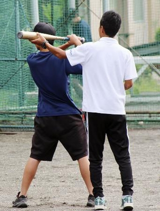　顧問を務める野球部の朝練習で、生徒のフォームを指導する